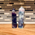 Two crystal towers on a wooden surface with a tiled wall background