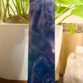 Extra Large Rainbow Fluorite tower  with bright blue, purple and green with green plants in the background