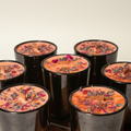 Decorative candles with floral elements in black holders on a wooden surface.