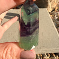 Hand holding a multicolored crystal prism outdoors