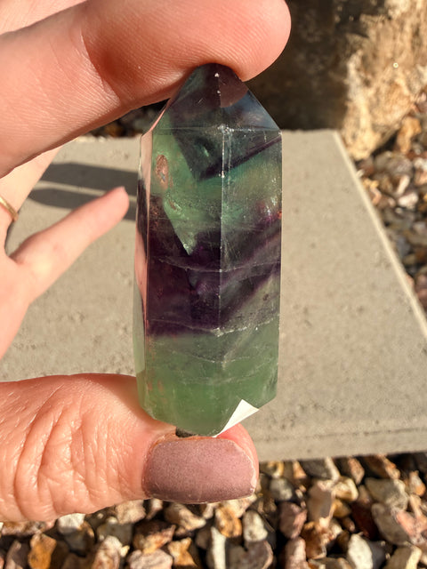 Hand holding a multicolored crystal prism outdoors