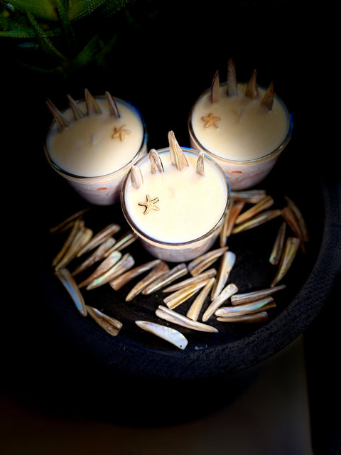 Three small candles with star-shaped wicks on a dark surface